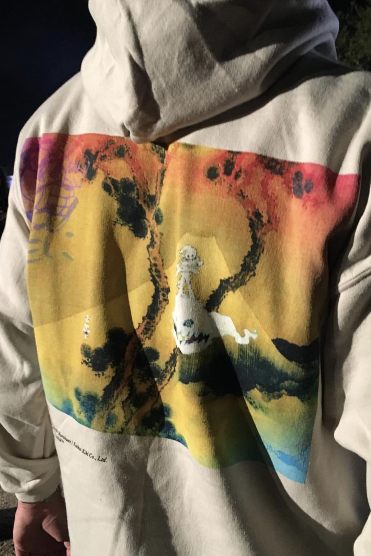 The Kids See Ghosts hoodie prints its own credits: Murakami’s art, Virgil’s layout. Sand, the back print on a guest's hoodie, Los Angeles listening party, June 2018.