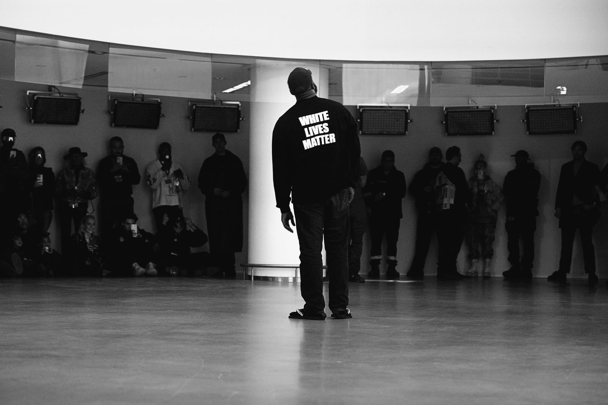 Ye gatecrashed Paris Fashion Week with YZY SZN 9 and a “White Lives Matter” shirt. Ye on the show floor at YZY SZN 9, back to camera, in the black long sleeve with the slogan on the back.