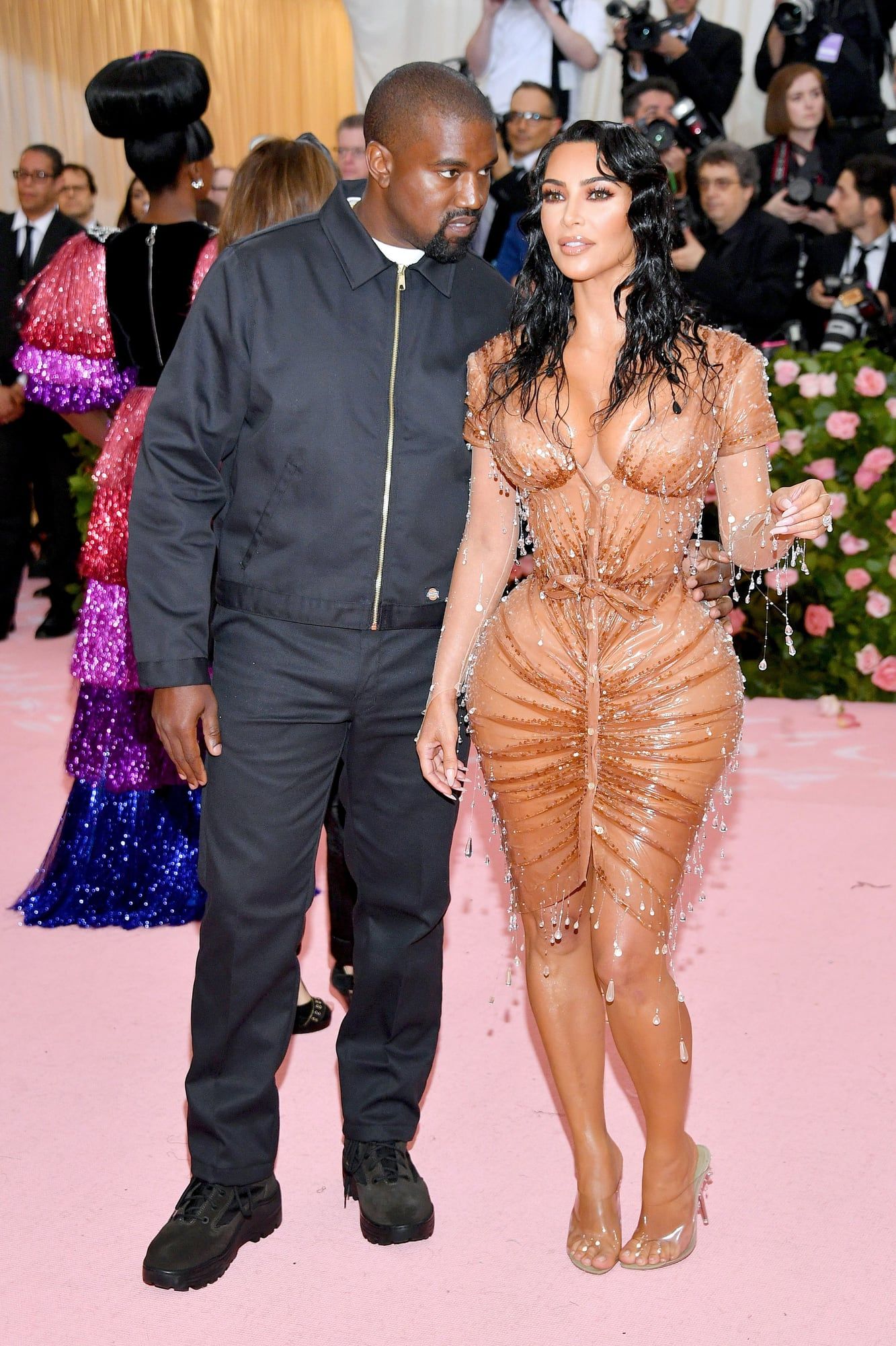 The Met asked for camp. Ye showed up in a Dickies work jacket. Ye full length on the Met Gala carpet in the black Dickies Eisenhower jacket over a white tee, black trousers and black boots, beside Kim Kardashian in custom Thierry Mugler, 6 May 2019.