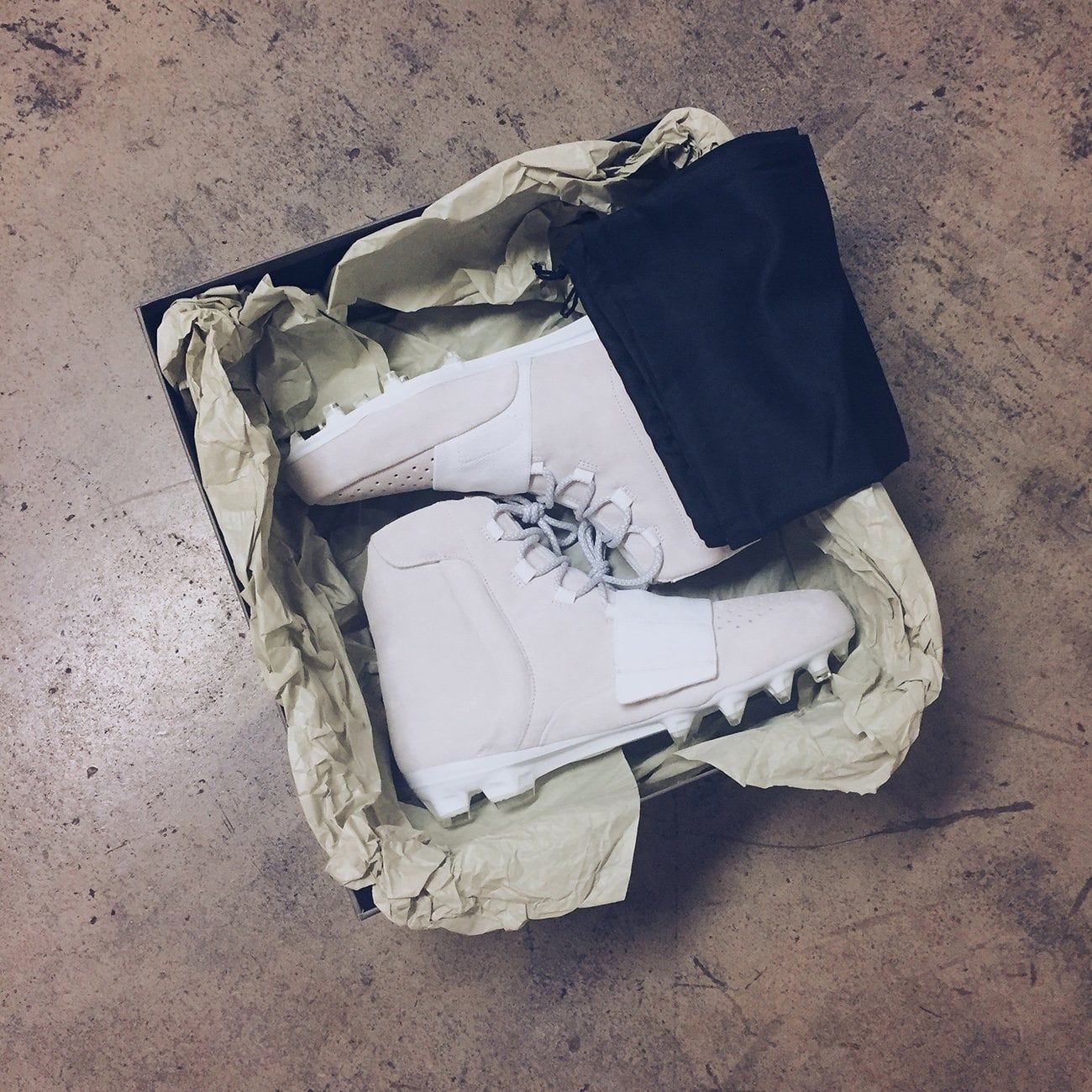 Von Miller warmed up in the first Yeezy cleat, then played in something else. Miller's pair in the box: off-white suede, forefoot strap, perforated toe, grey laces, white stud plate, 8 Sep 2016.