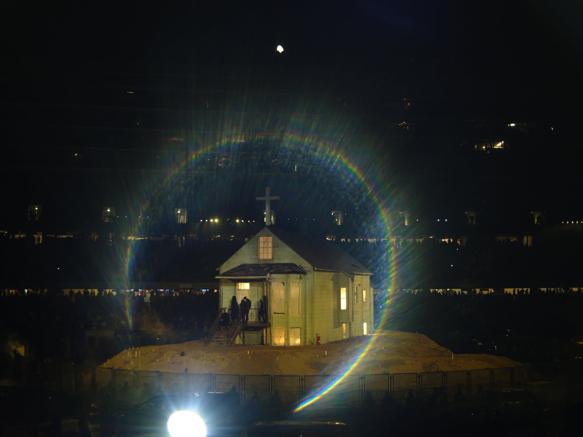 Ye rebuilt his childhood home inside Soldier Field, then walked out of it on fire. The replica of Ye's childhood home on its mound, cross on the roof, figures on the porch, Soldier Field, 26 Aug 2021.