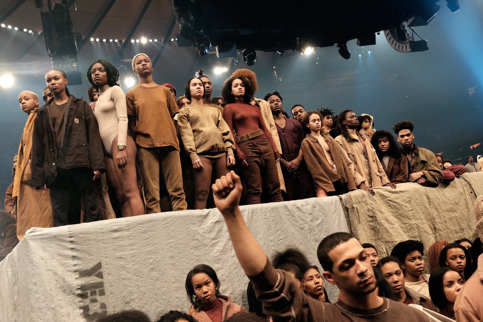 Ye sold out Madison Square Garden with an album nobody had heard. Yeezy Season 3 models on the platform in maroon, ochre and tan, a raised fist in the crowd, 11 Feb 2016.