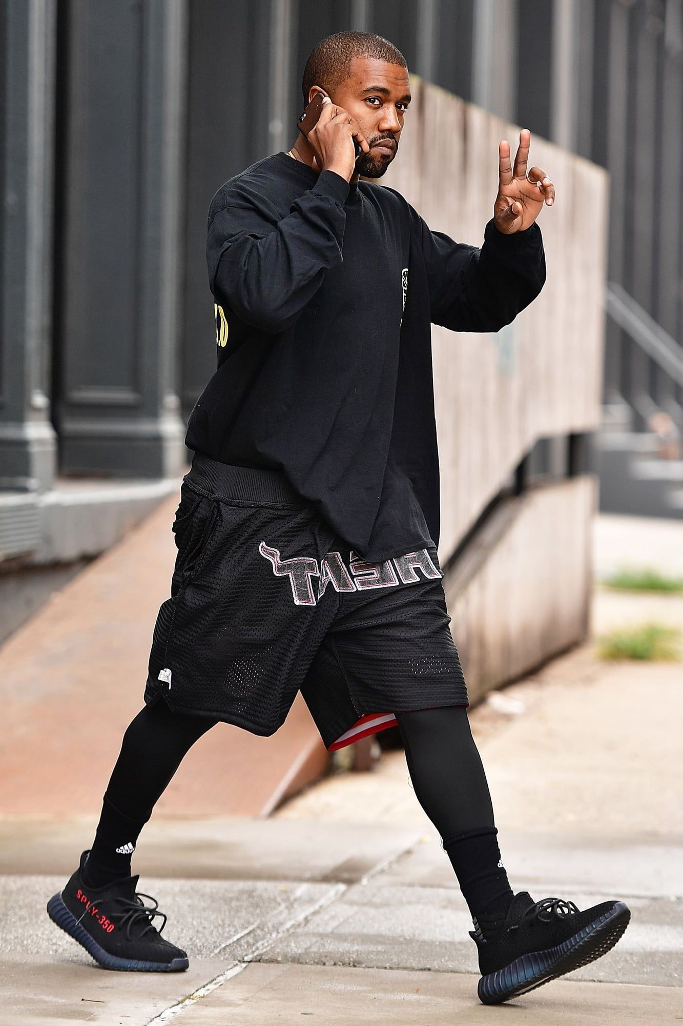The black 350 V2 lost a little more of its stripe every time. Ye mid-stride in the black and red 350 V2, black long sleeve, basketball shorts over leggings, New York, 1 Sep 2016.
